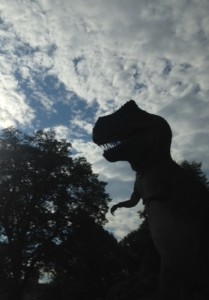 The dinosaur outside of the science museum silhouetted against the cloudy  morning sky.